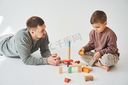 有爱心的爸爸和快乐的儿子一起玩白色背景的玩具木立方体。