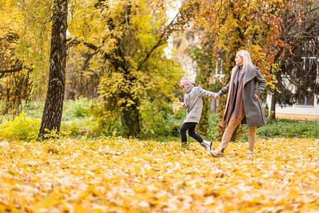 母亲和女儿在秋天的黄色公园。