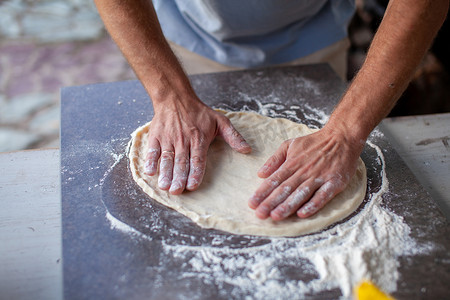 撒面粉摄影照片_在撒了面粉的石板上擀出披萨面团，在头顶拍摄