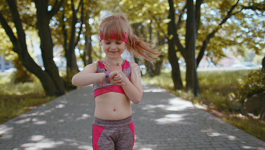儿童看手表摄影照片_运动跑步女孩看智能手表时钟设备健身手镯检查时间、心率