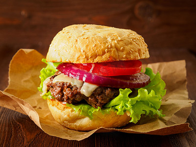 大汉堡摄影照片_美味的自制大汉堡，烤面包卷上有牛排、奶酪、洋葱、西红柿和生菜。