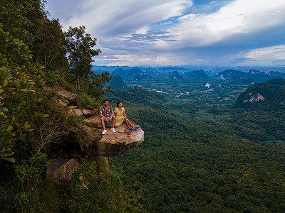 泰国甲米的龙冠山，一位年轻的旅行者坐在悬于深渊的岩石上，风景秀丽。 