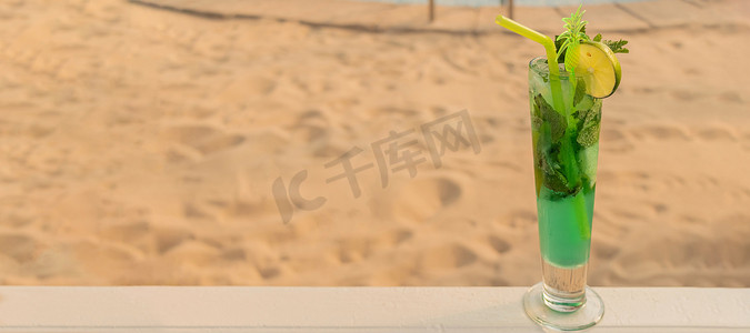 横幅与热带绿色鸡尾酒与稻草、 薄荷和石灰在金色的沙滩背景。