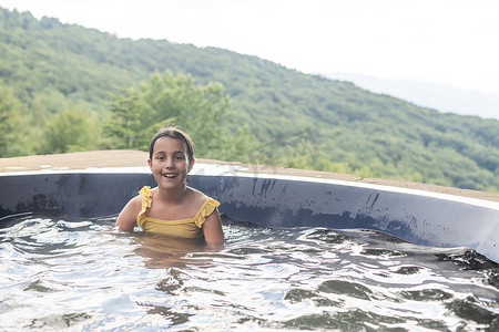 夏天，小女孩在山里的热水浴缸里。