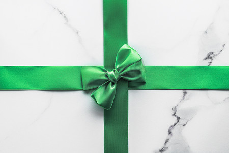大理石背景上的绿色丝带和蝴蝶结、圣帕特里克节礼物或奢华数字品牌的圣诞魅力礼品装饰、假日平铺设计