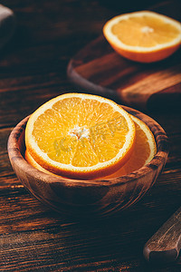 切橙子摄影照片_在一个木碗里切橙子
