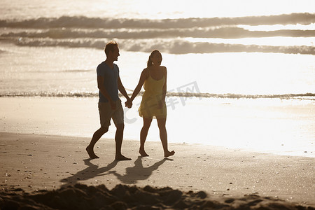 行走的女人摄影照片_在海滩上浪漫地散步。
