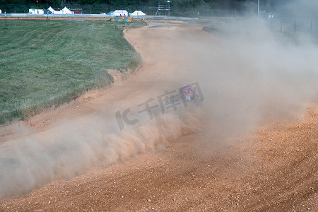 灰尘飞扬摄影照片_越野车赛道上的越野车、打滑、轮胎下飞扬的灰尘和污垢