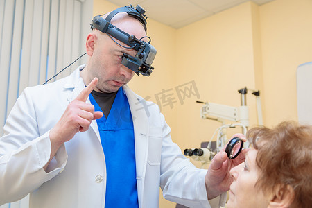 男性眼科医生用双目检眼镜检查成年女性的视力