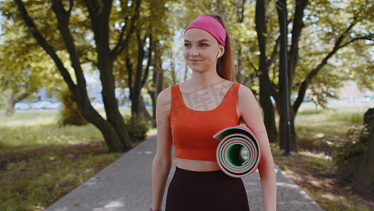 运动健身运动跑步女孩带着运动瑜伽垫走路做健身伸展运动