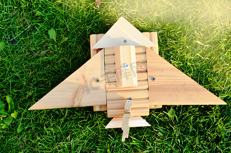 顶视图，平花环，阳光明媚的绿草上的木制自制玩具飞机，自驾旅行概念，点亮