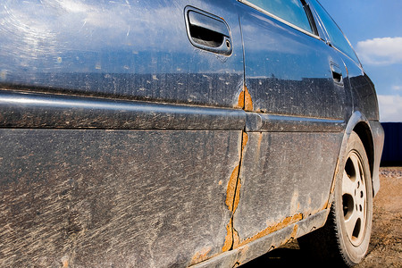 一辆肮脏的损坏汽车的司机金属门上的锈迹，汽车摊销