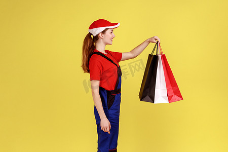 快递女人手里拿着购物袋站着，表达幸福的侧视肖像。