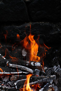 消防安全火焰摄影照片_燃烧的木头，火焰仍在燃烧，营火或烤架的深石背景
