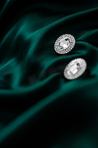 深翠绿色丝绸上的豪华钻石耳环，节日魅力珠宝礼物