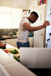 我觉得我错过了一些东西......一个英俊的年轻人在家里的厨房做早餐时看着他的冰箱的镜头。