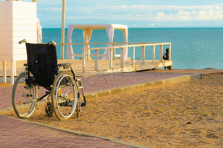 轮椅残疾人摄影照片_更衣室度假海滩海上轮椅残疾人快乐旅行家庭生活方式，成人和日出椅概念度假夏季，特殊人群。