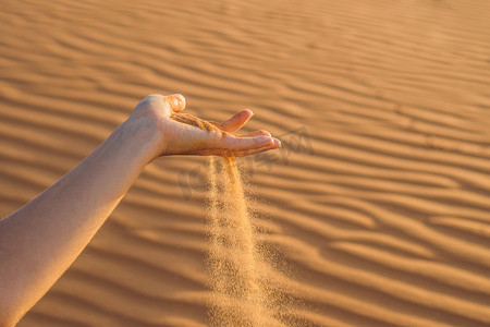沙子从沙漠中女人的手指间滑过