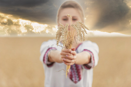 夕阳的天空背景下，手里拿着小麦的女孩