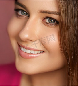 美妆护肤化妆品摄影照片_粉红色背景中的美容、化妆和护肤化妆品模特脸像、自然妆容的微笑女性、完美健康的牙齿、牙科护理
