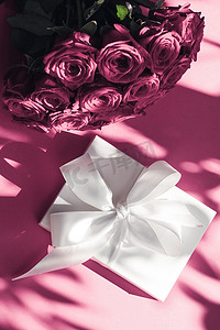 礼盒惊喜摄影照片_豪华假日丝绸礼盒和粉色背景玫瑰花束、浪漫惊喜和鲜花作为生日或情人节礼物