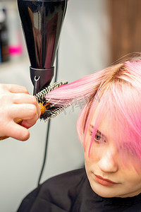 美发师吹干女人的粉红色头发