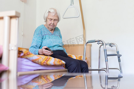 96 岁的老妇坐在医疗床上，由持有人扶着她阅读电话留言。