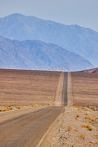 空旷平原上漫长而空旷的沙漠路通往大山