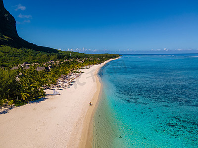 Le Morne 海滩毛里求斯，带棕榈树和白色沙滩蓝色海洋的热带海滩和带雨伞的沙滩床、太阳椅和遮阳伞在热带海滩的棕榈树下，Le Morne 海滩毛里求斯