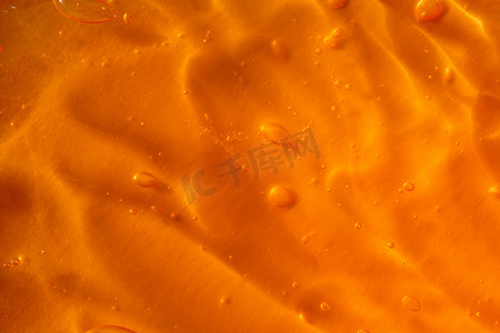 透明发光气泡摄影照片_橙色背景上带气泡和波浪的透明黄色凝胶的质地