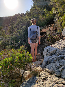 年轻活跃的女性游客穿着小背包，在松树间的沿海小路上行走，寻找偏远的海湾，在克罗地亚的海边和平地独自游泳。