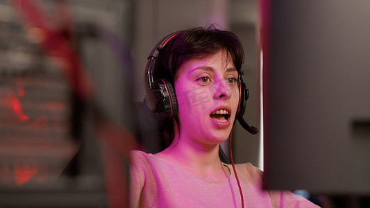游戏玩家女孩在向订阅者解释游戏玩法时用耳机交谈的手持镜头