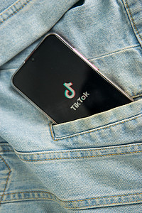 牛仔夹克摄影照片_2020 年 5 月 7 日，俄罗斯特维尔，智能手机屏幕上的 tik tok 标志从牛仔夹克的口袋里伸出来。 