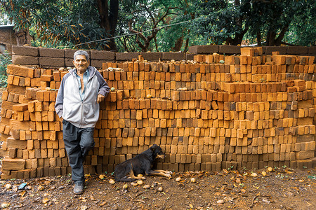 尼加拉瓜农村地区，一位老人和他的狗一起躺在一堆红砖上