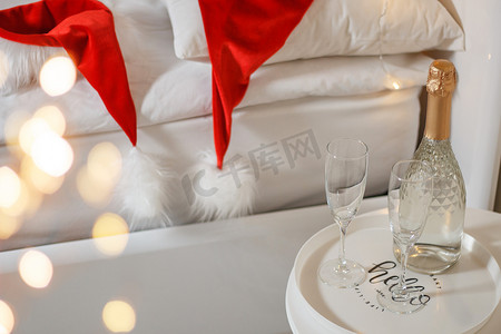 香槟图案摄影照片_圣诞装饰的酒店房间里有两杯和一瓶香槟。