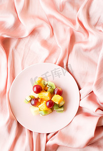 丝绸上的多汁水果沙拉，平铺-健康的生活方式和床上早餐概念