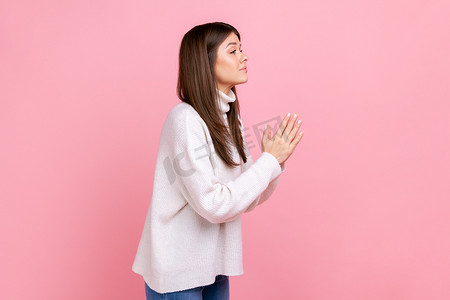 漂亮女孩的侧视肖像，双臂保持祈祷姿势，请求宽恕，感到抱歉。