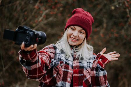 微笑的旅游博主女性制作新的视频博客，vlog，她的相机在自然森林背景下。