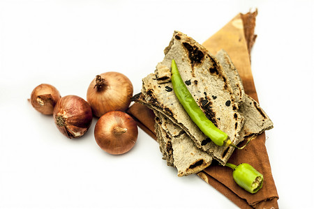 穷人的午餐或农民的午餐用白色隔离，或者午餐中吃的常见物品用白色隔离，这些食物是 bajri ki roti，配切洋葱和生洋葱以及青辣椒。