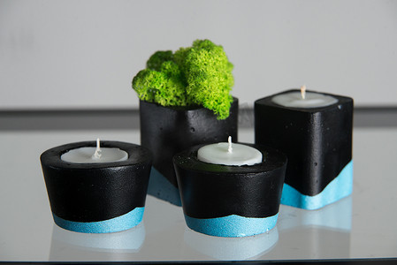 黑色和蓝色混凝土烛台中的蜡烛和苔藓