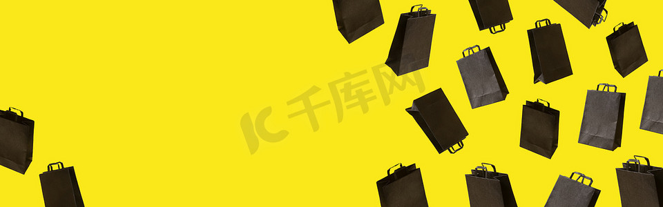 星期五黄色摄影照片_带有黑色销售购物袋的横幅在黄色背景上飘扬。