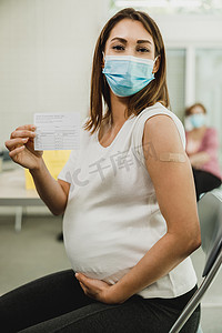 记录卡摄影照片_持有 Covid-19 疫苗接种记录卡的孕妇