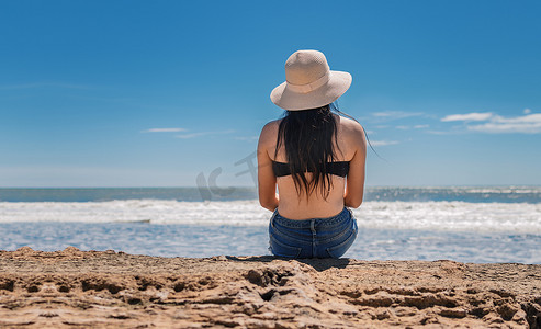 戴帽子的女人从背到海，戴帽子的女孩望海，度假概念，看海的女孩的后视图