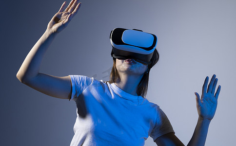vr虚拟现实摄影照片_戴着 VR 耳机的女人试图触摸虚拟现实中的物体。