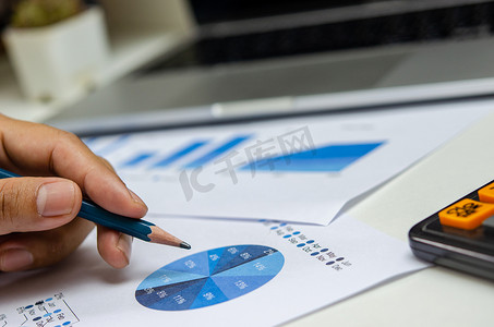 业务文档图财务报告统计分析和图表投资信息与办公室办公桌上的笔记本电脑。