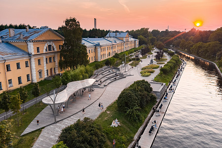 日落时，俄罗斯圣彼得堡卡尔波夫卡河堤公园的鸟瞰图、休闲区、长椅和圆形剧场、公园对面的植物园