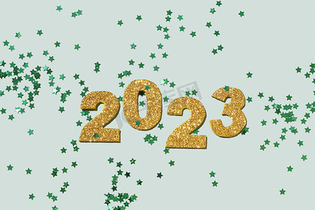 柔和的绿色背景上闪亮的金色数字 2023。