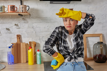 金发女郎戴着防护手套，在家里的厨房里拿着抹布清洁电炉。