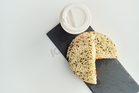 咖啡店的桌子上放着一个三明治，上面放着一杯红色塑料咖啡。