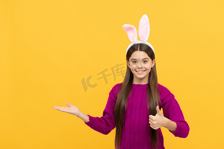复活节快乐的少女，戴着滑稽的兔子耳朵，展示产品、复制空间、复活节快乐